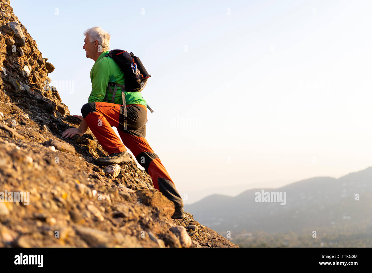 Senior man hiking a mountain during sunny day Stock Photo