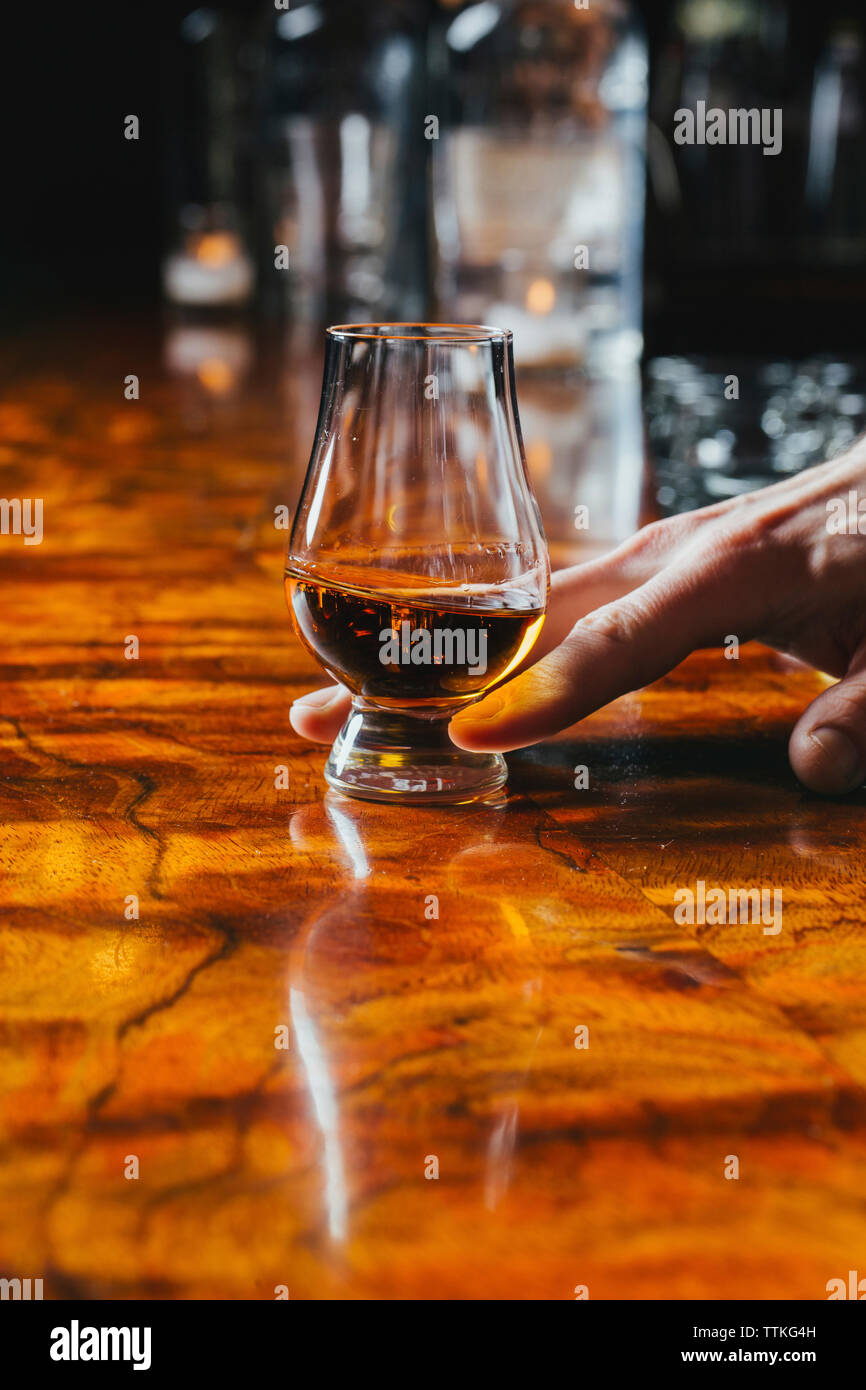 Cropped hand of bartender holding drink on bar counter Stock Photo