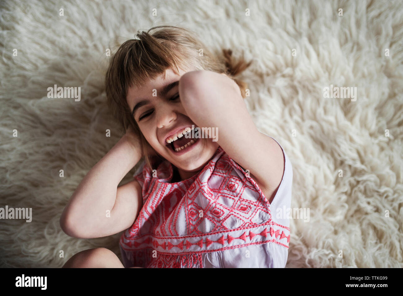 Overhead view of cheerful girl lying on rug at home Stock Photo Alamy