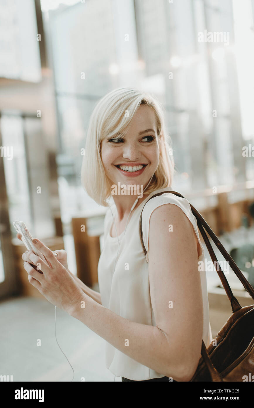 Happy woman looking away while using mobile phone in cafe Stock Photo