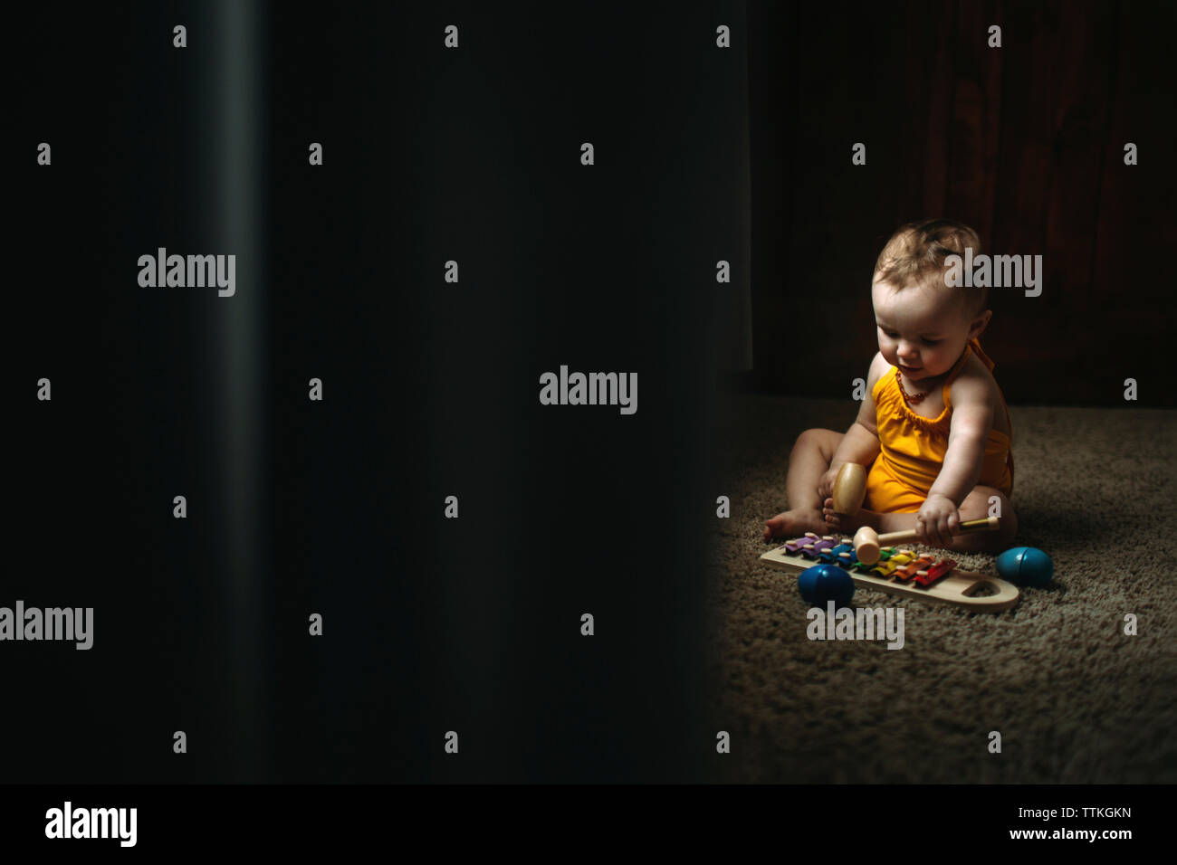 Baby girl playing xylophone while sitting on rug at home Stock Photo
