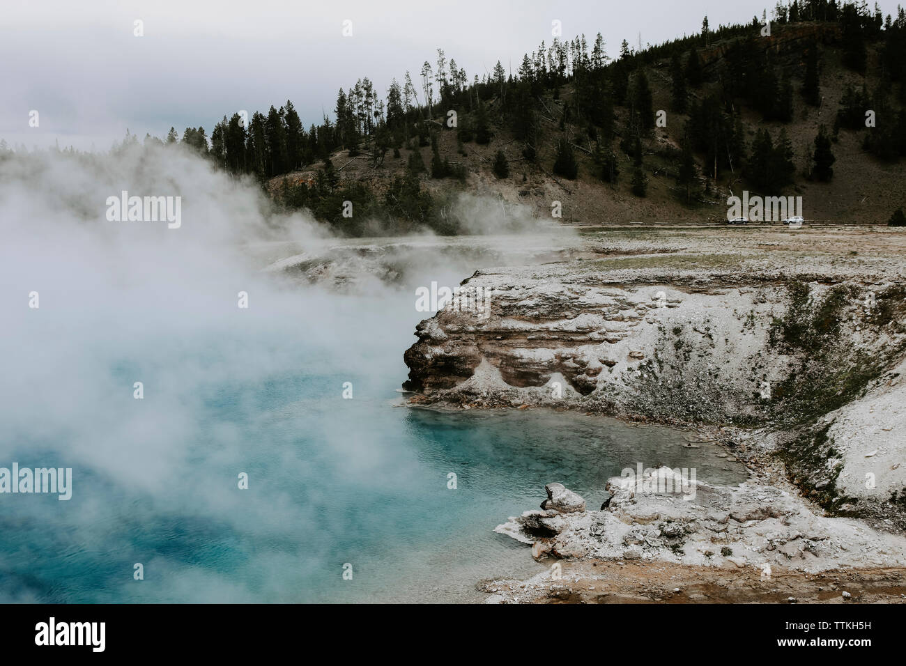 Smoke emitting from hot spring against mountain at Yellowstone National Park Stock Photo