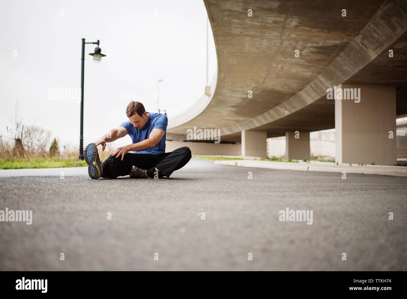 Determined man exercising while sitting on street Stock Photo