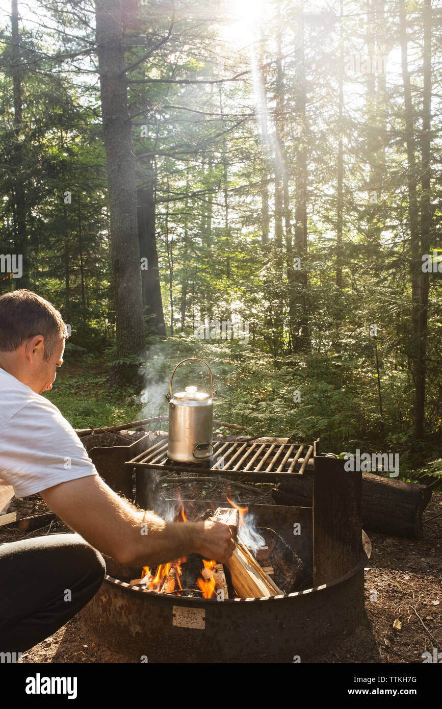 Rear view of man preparing food in barbecue at forest Stock Photo