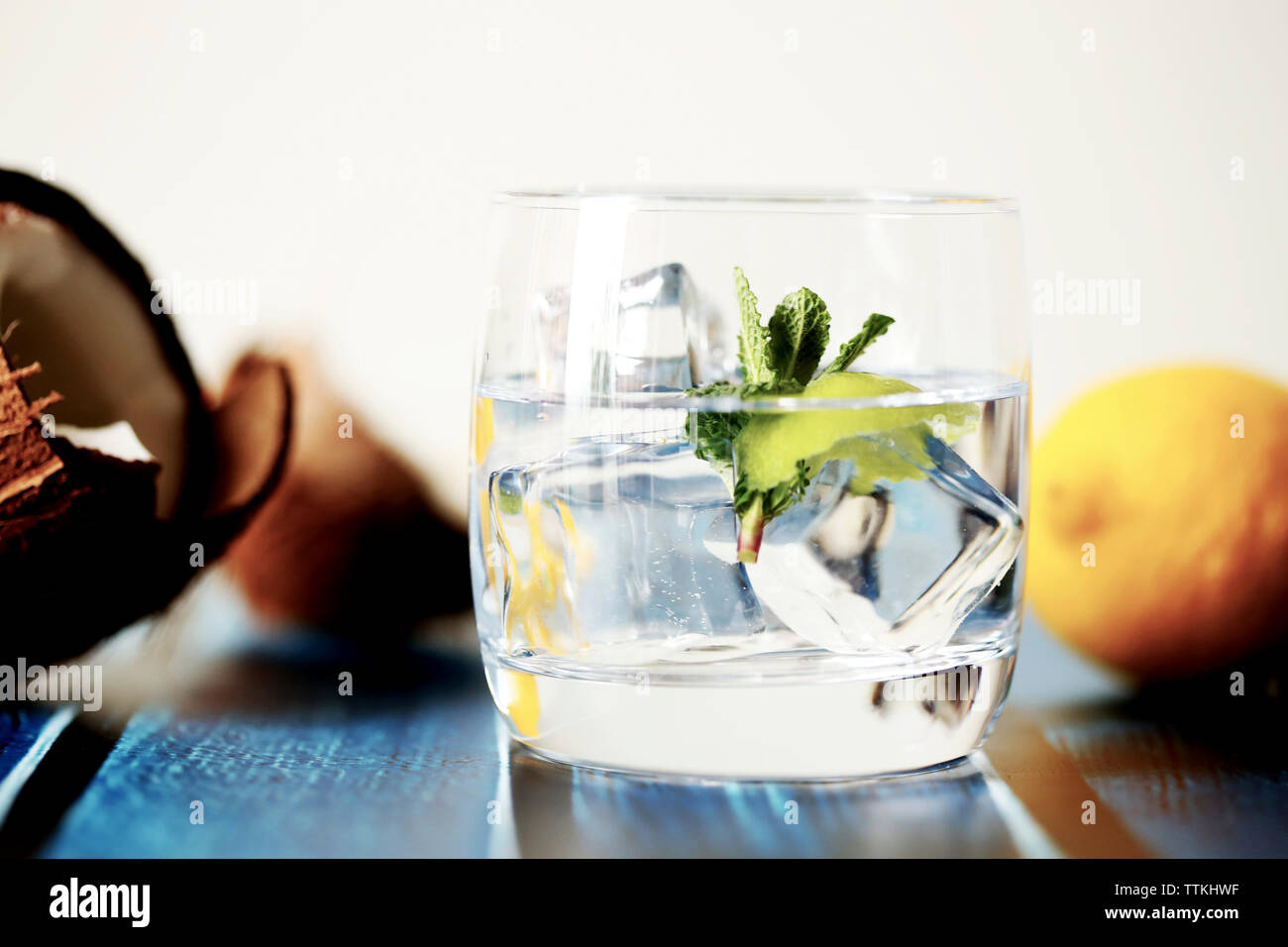 Close-up of ice cubes in drink with fruits on table against white background Stock Photo