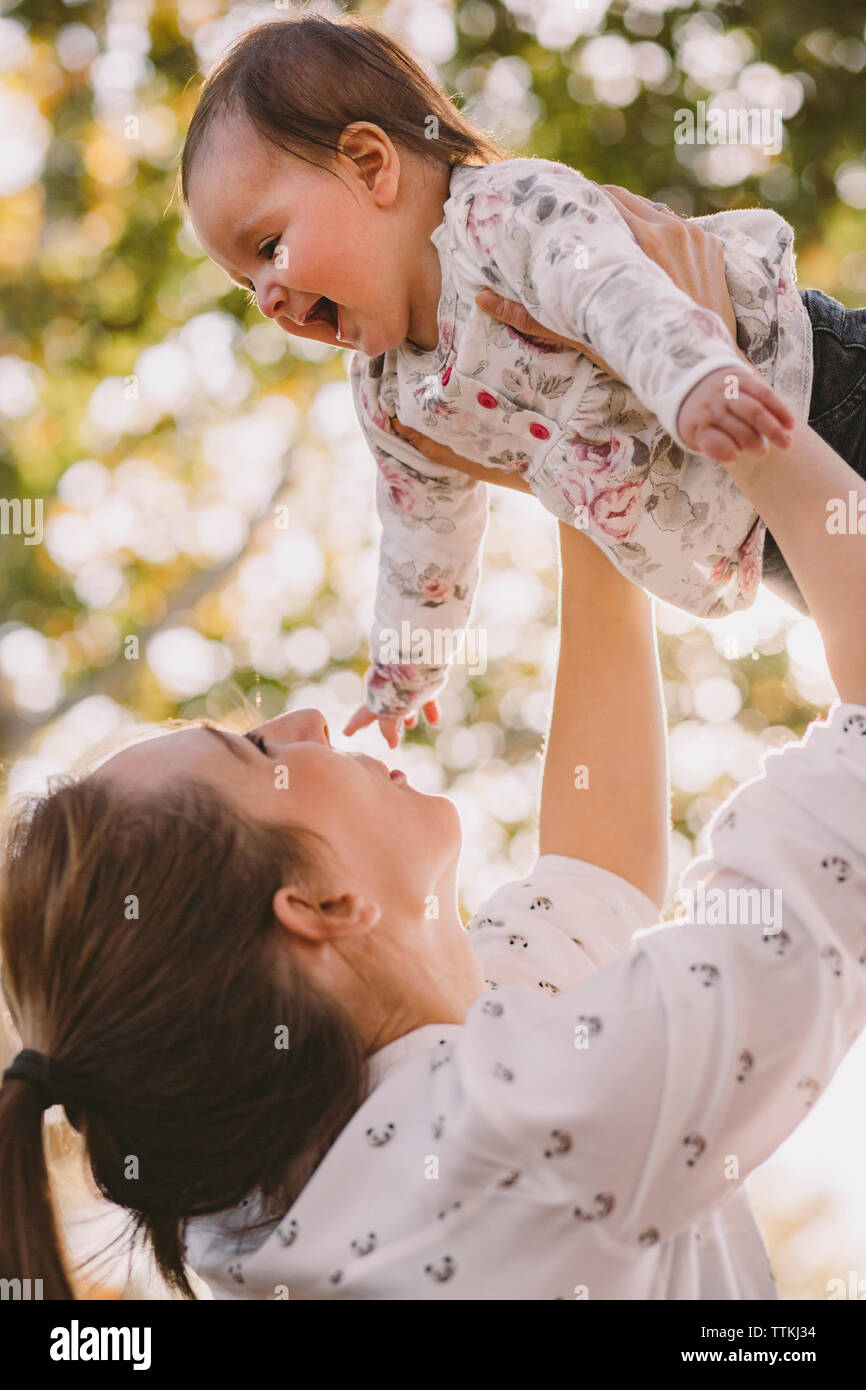 Low angle view of happy mother picking up cute daughter at park Stock Photo