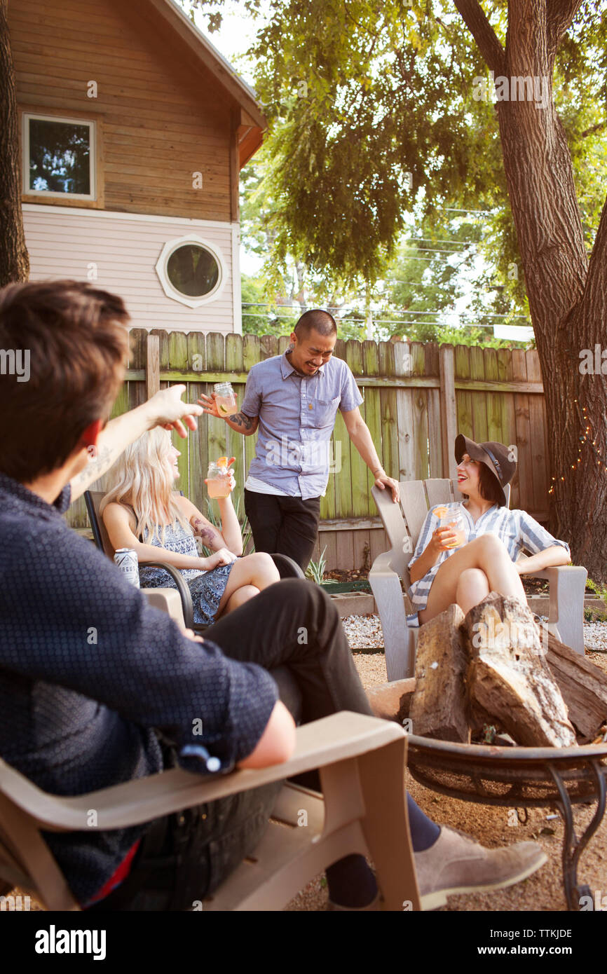 Cheerful friends having drinks in yard Stock Photo