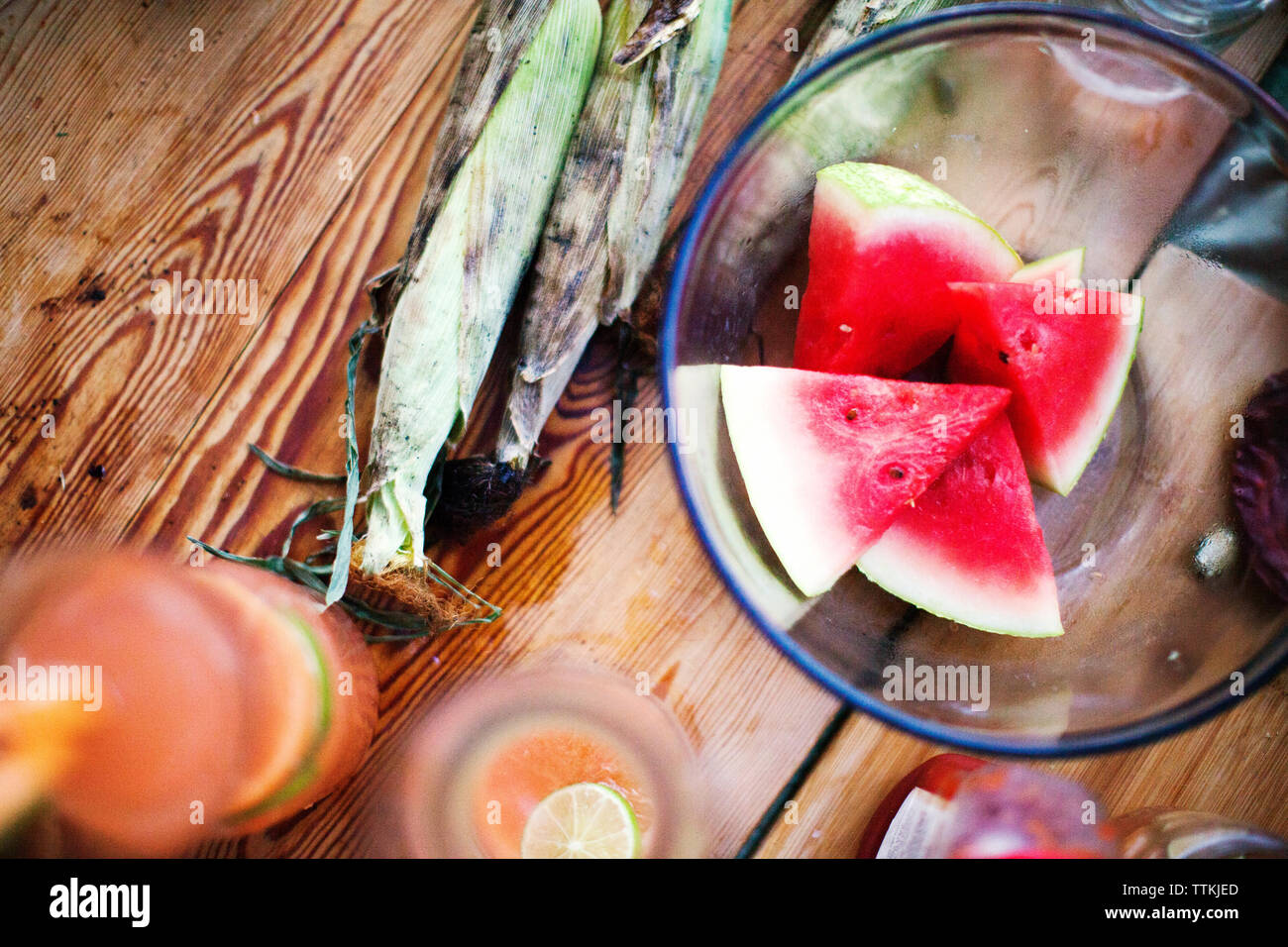 Overhead view of watermelon slices in bowl by corns on table Stock Photo