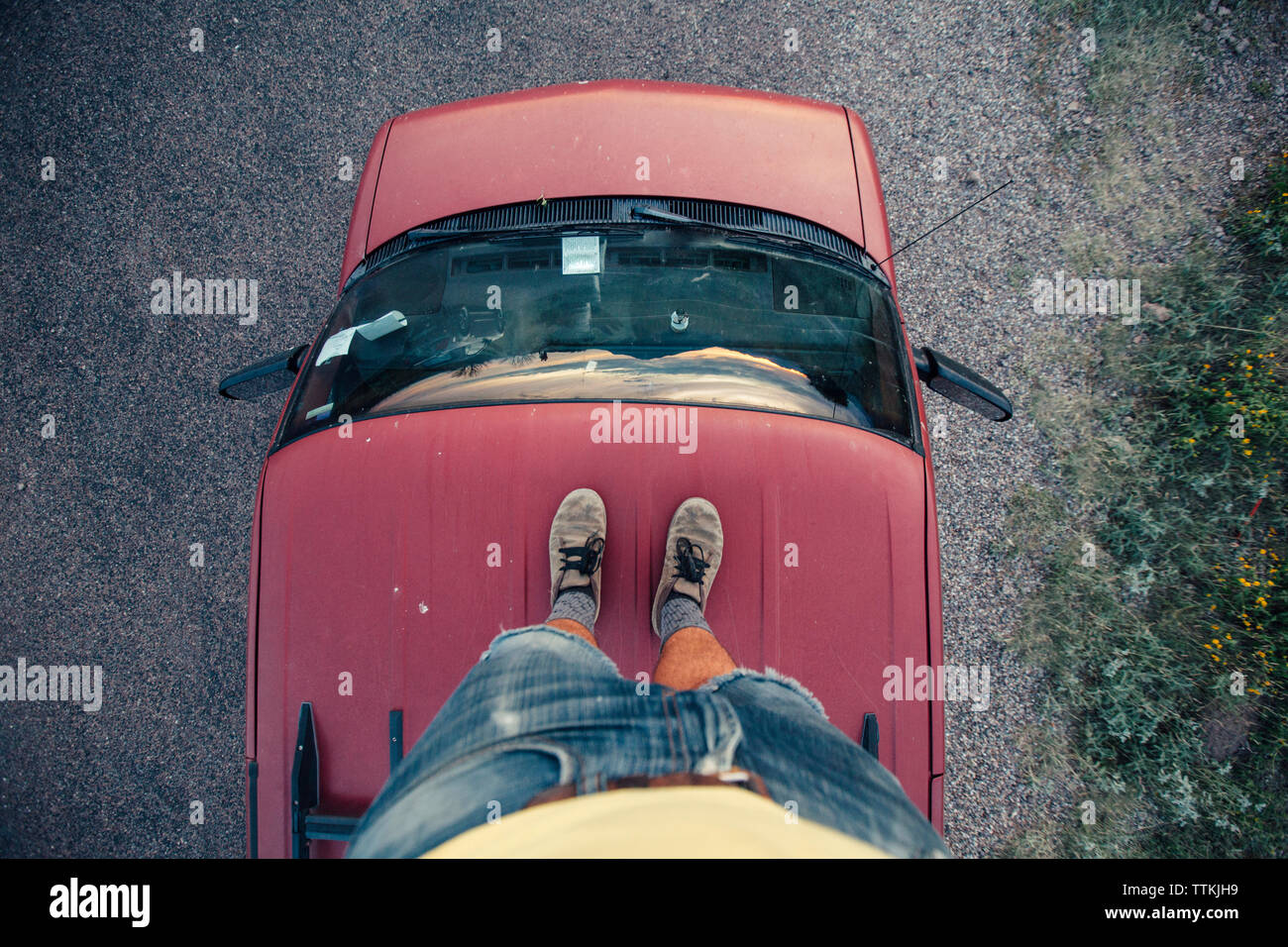 Low section of man standing on red car roof Stock Photo