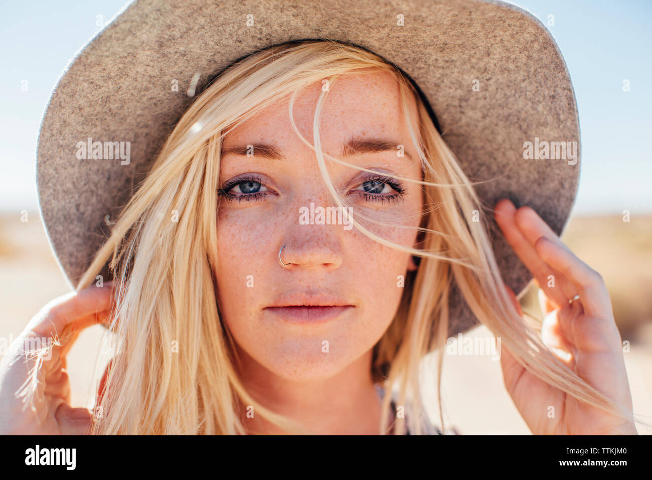 Close-up portrait of woman in sun hat enjoying vacation at desert on sunny day Stock Photo