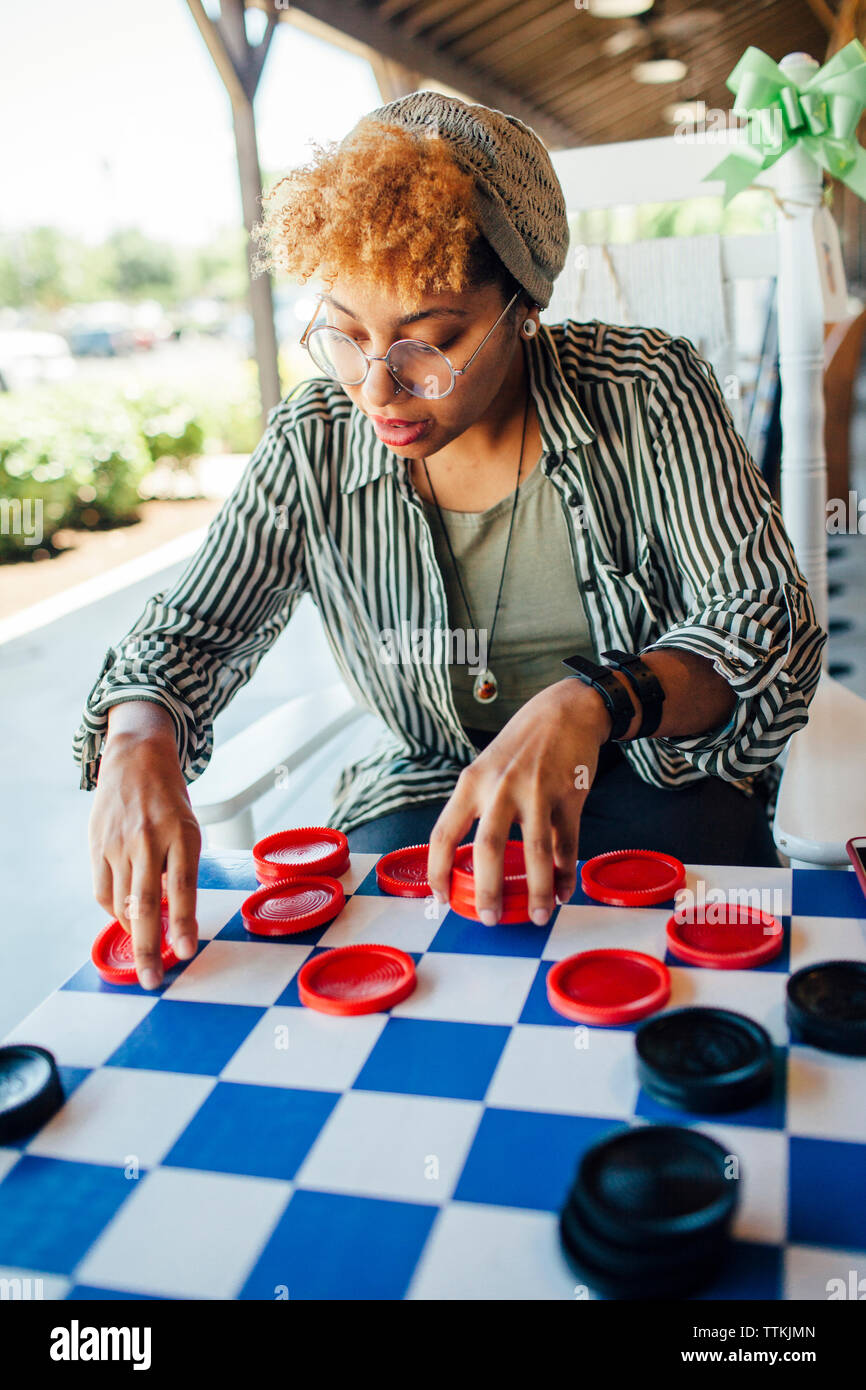 Woman playing checkers while sitting at yard Stock Photo