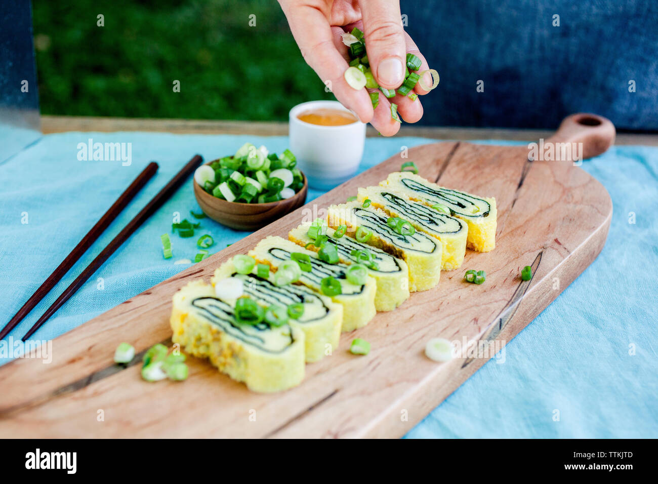 Cropped hand of female chef garnishing baked pastry item on serving board in commercial kitchen Stock Photo
