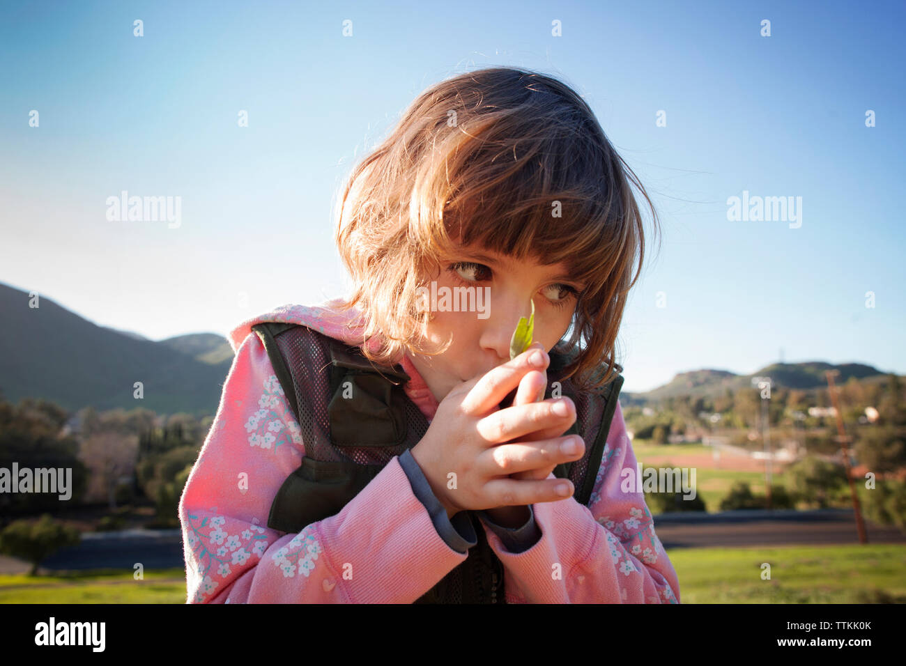 Close-up of girl with hands clasped on field against clear sky Stock Photo