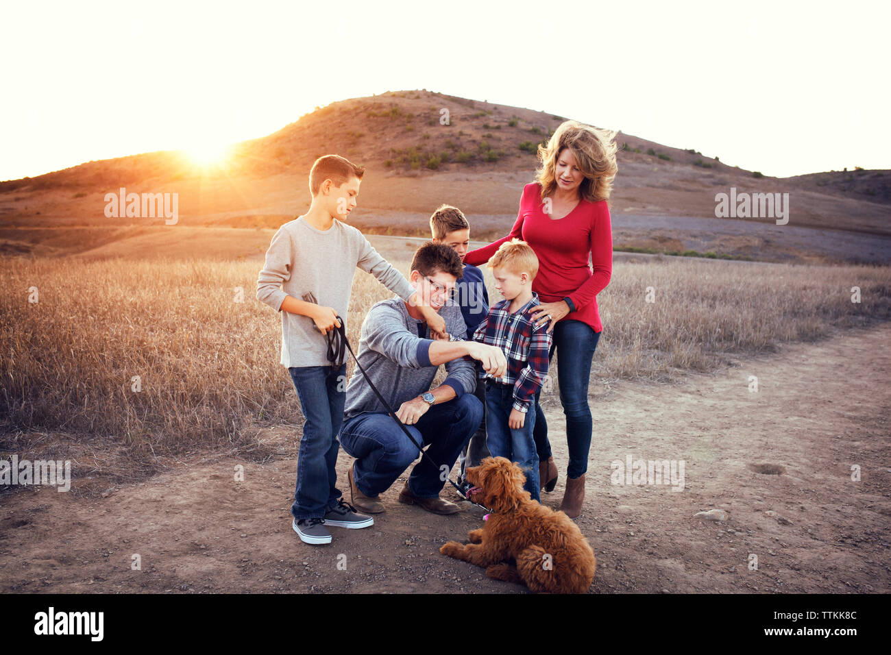 Family with dog enjoying on field against mountains on sunny day Stock Photo