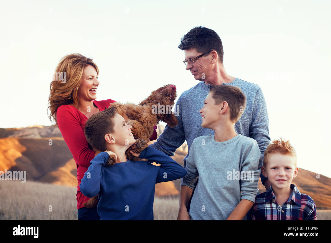 Happy family with dog standing on field against clear sky Stock Photo