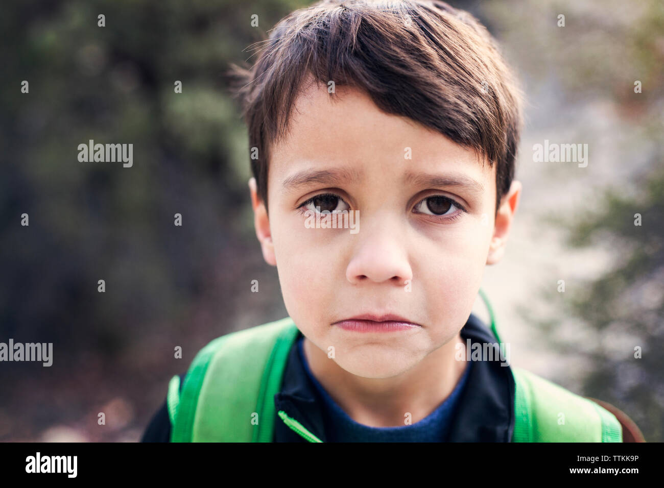 Portrait of sad boy standing outdoors Stock Photo