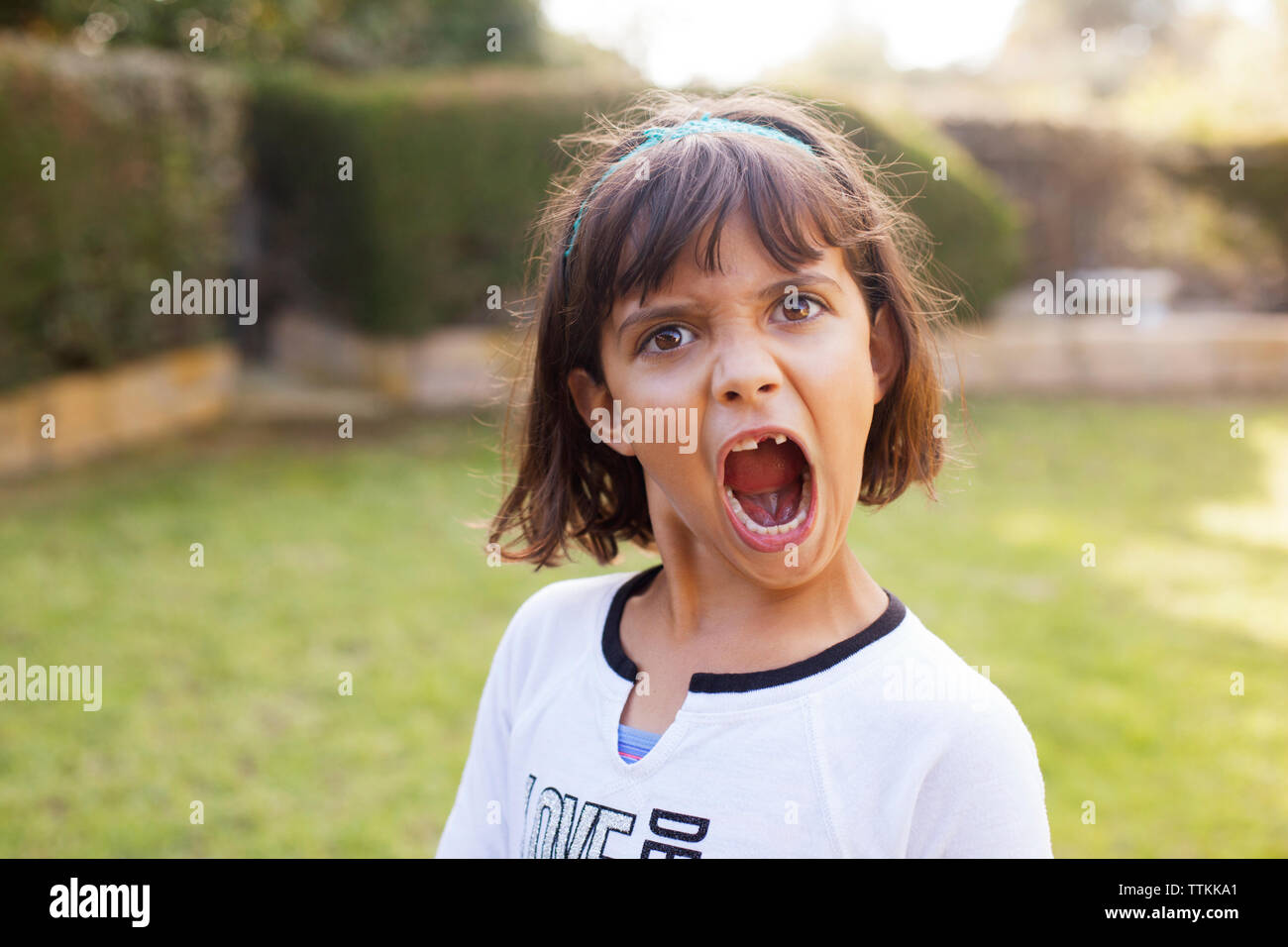 Portrait of playful girl shouting in yard Stock Photo