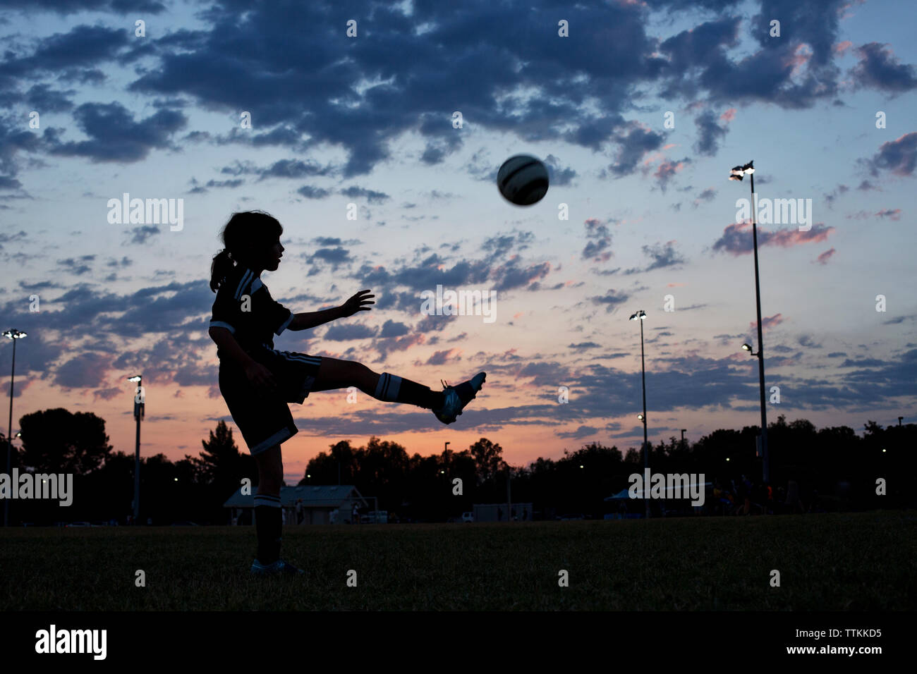 Side view of girl kicking soccer ball at field against sky during sunset  Stock Photo - Alamy