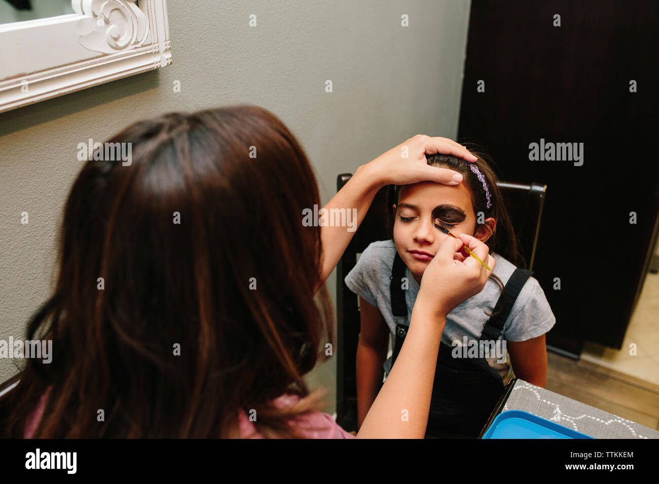 Woman applying make-up on daughter's face at home Stock Photo