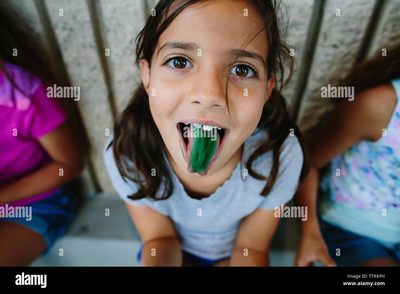 Portrait of girl showing green candy colored tongue Stock Photo
