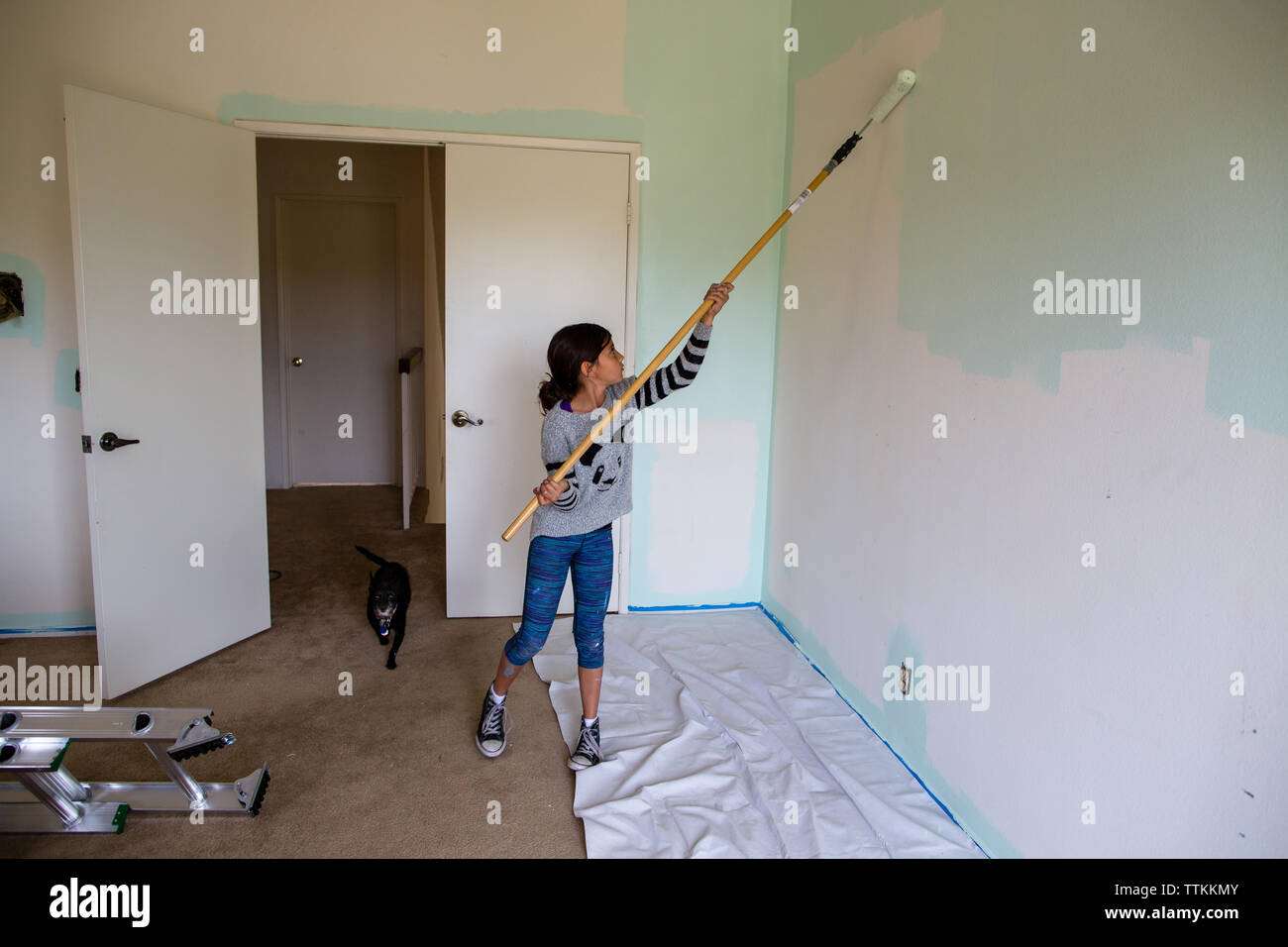 Girl painting wall using paint roller at home Stock Photo