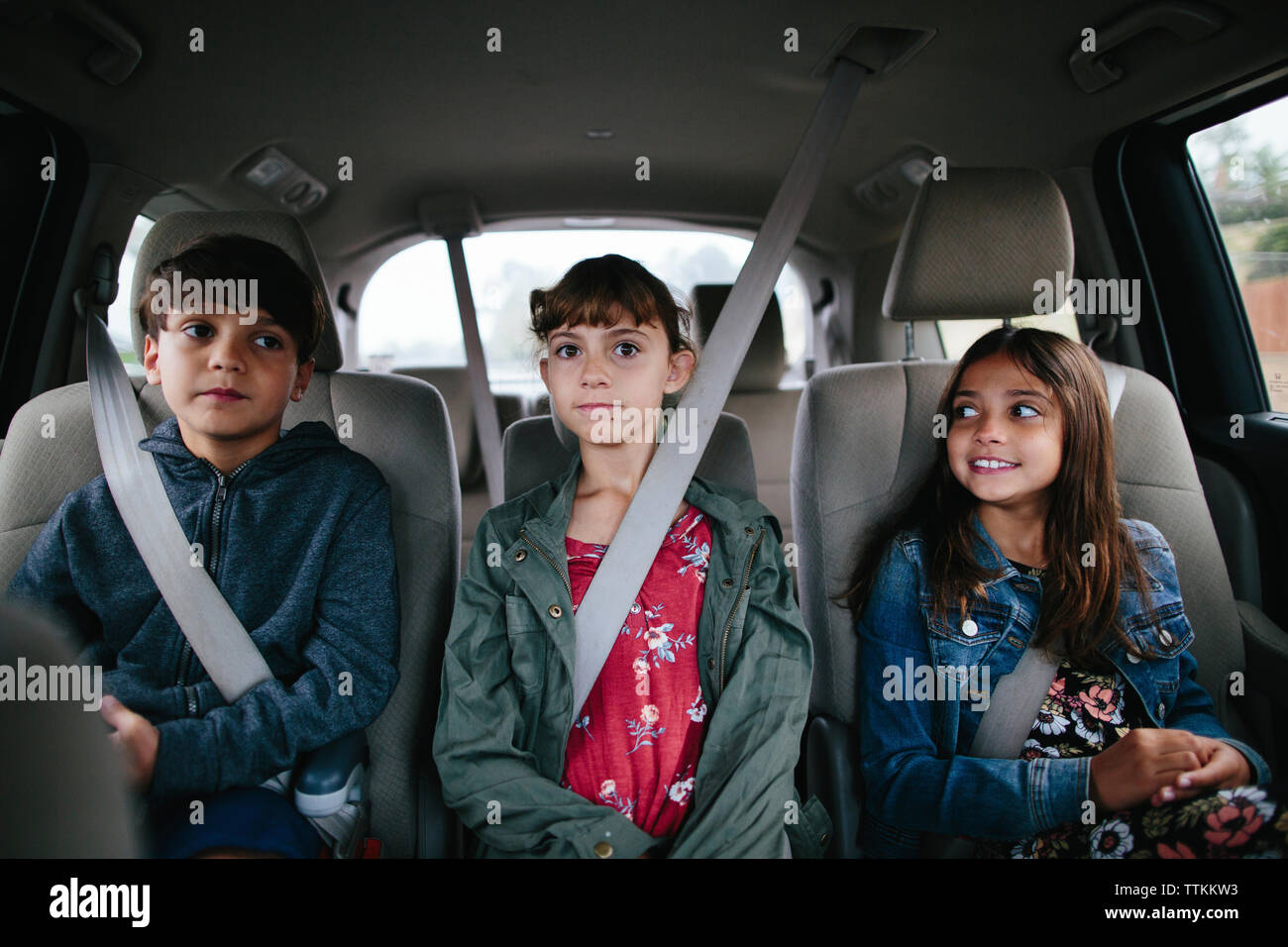 Siblings sitting side by side in car Stock Photo