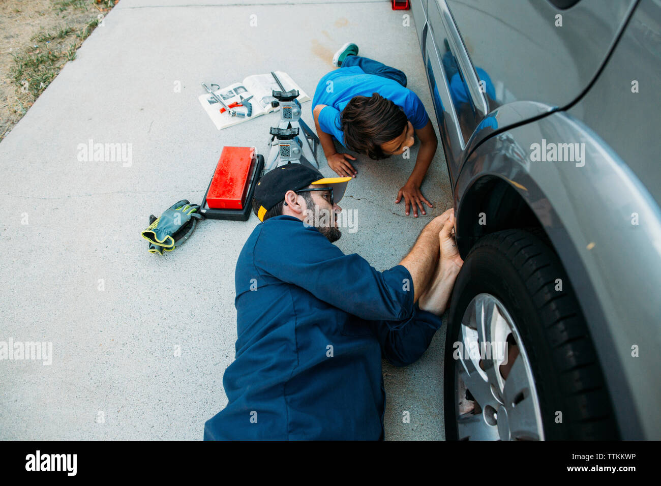 High angle view of father teaching son to repair car at driveway Stock Photo
