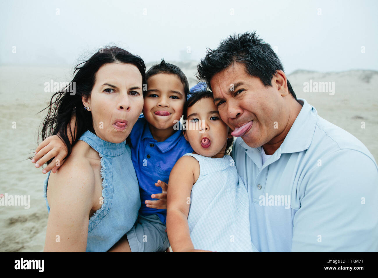 Family Of Four Make Silly Faces For Camera At Foggy Beach Stock Photo