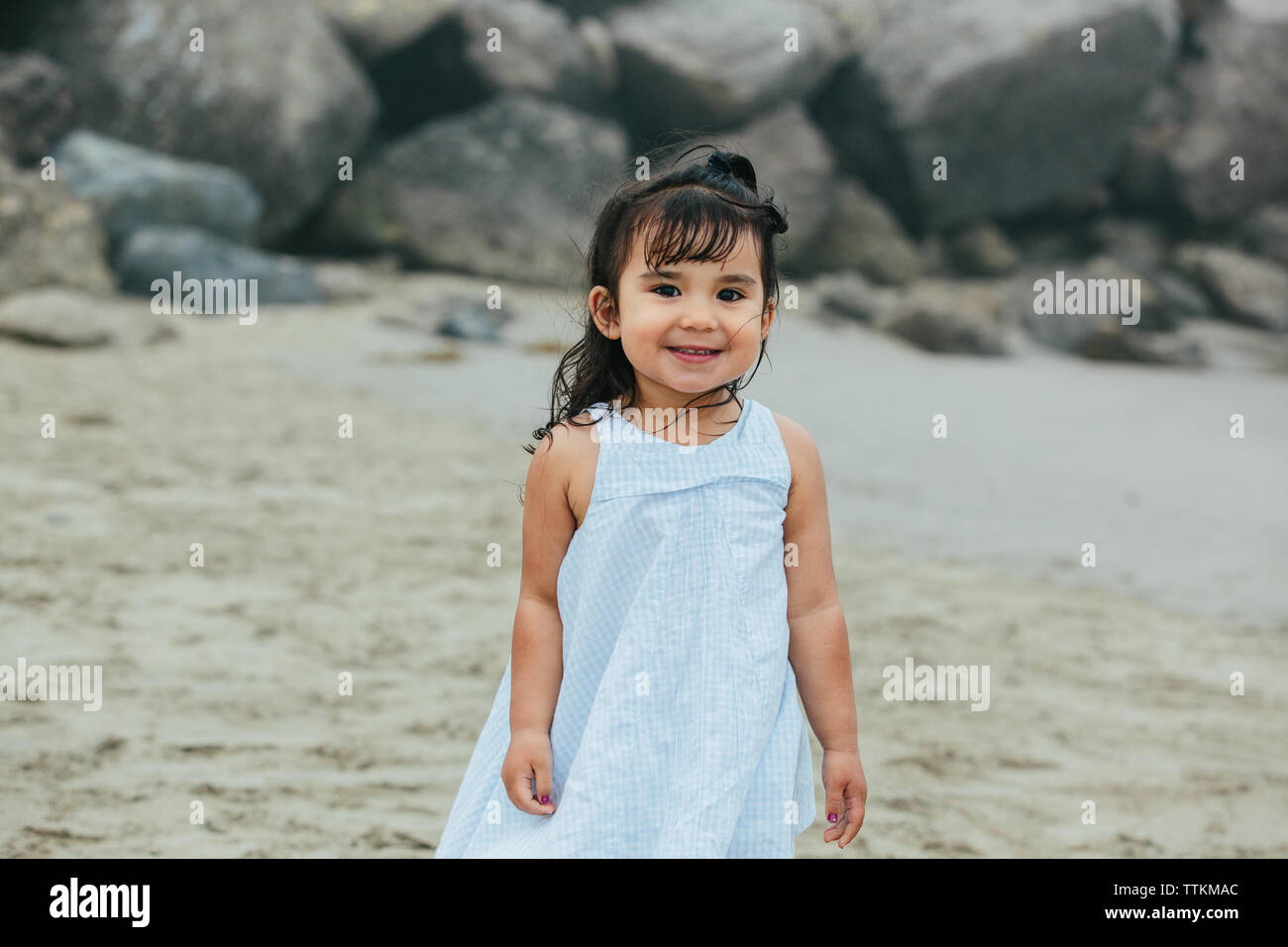 Cute Ethnically Ambiguous Toddler Girl Smiles For Camera At Beach Stock Photo