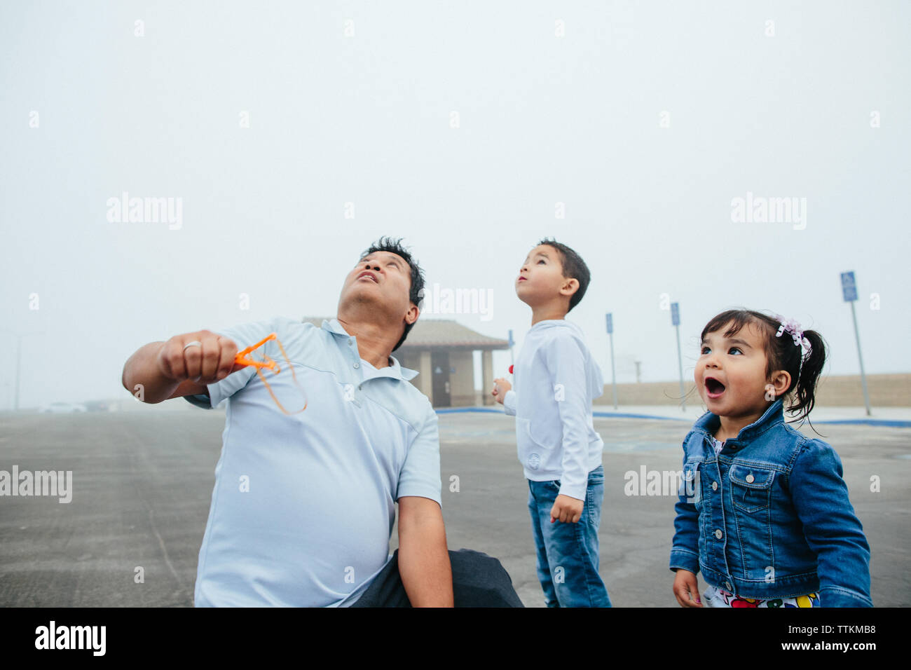 Father Holding Slingshot with Daughter And Son Daughter In Awe Stock Photo