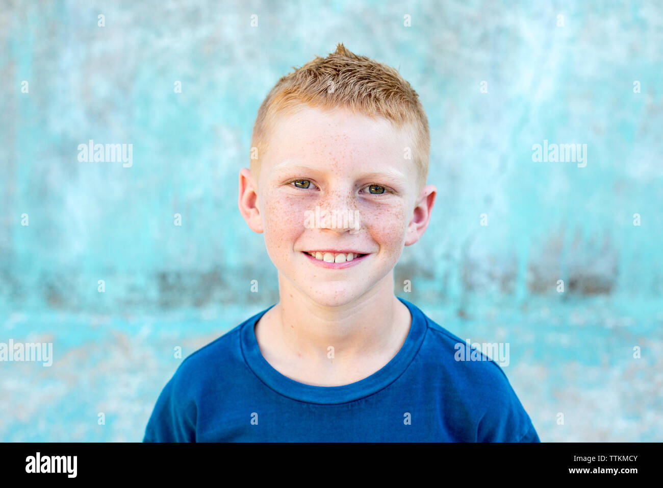 Portrait of a red head boy with freckles with a blue background Stock Photo
