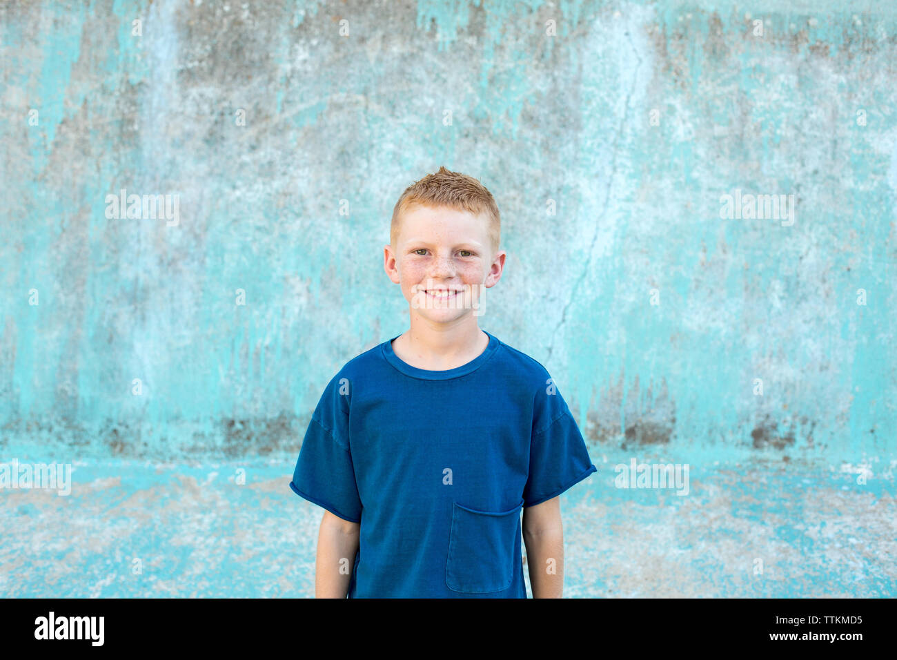 Portrait of a boy with red hair with a blue shirt and blue background Stock Photo