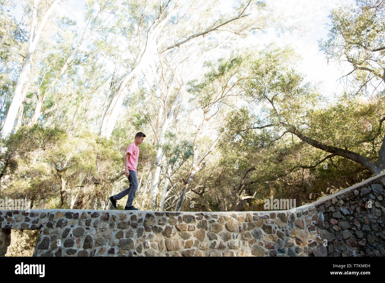 Teenage boy walks on top of a stone wall Stock Photo