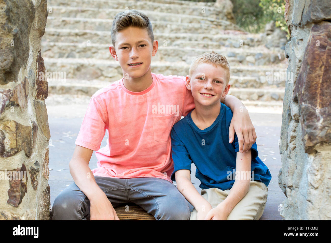 Older brother with arm around younger brother sit for portrait Stock Photo