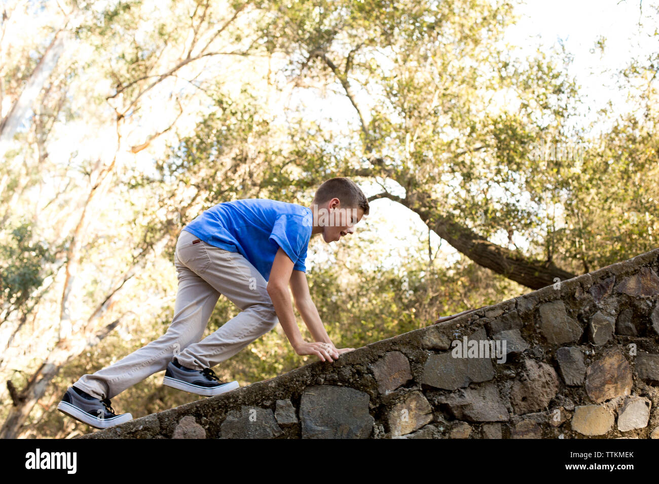 Boy climbs on top a stone wall Stock Photo