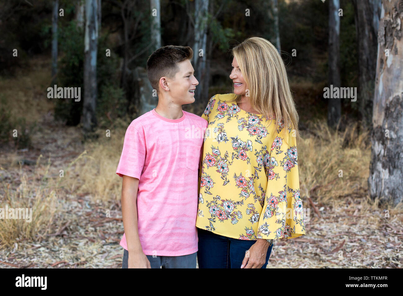 Mother and teenage son smile at each other while standing close Stock Photo