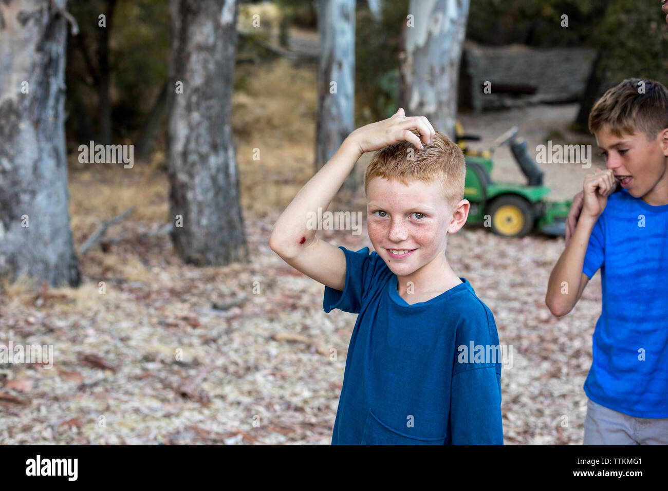 Boy with red hair and freckles touches his head and smiles Stock Photo