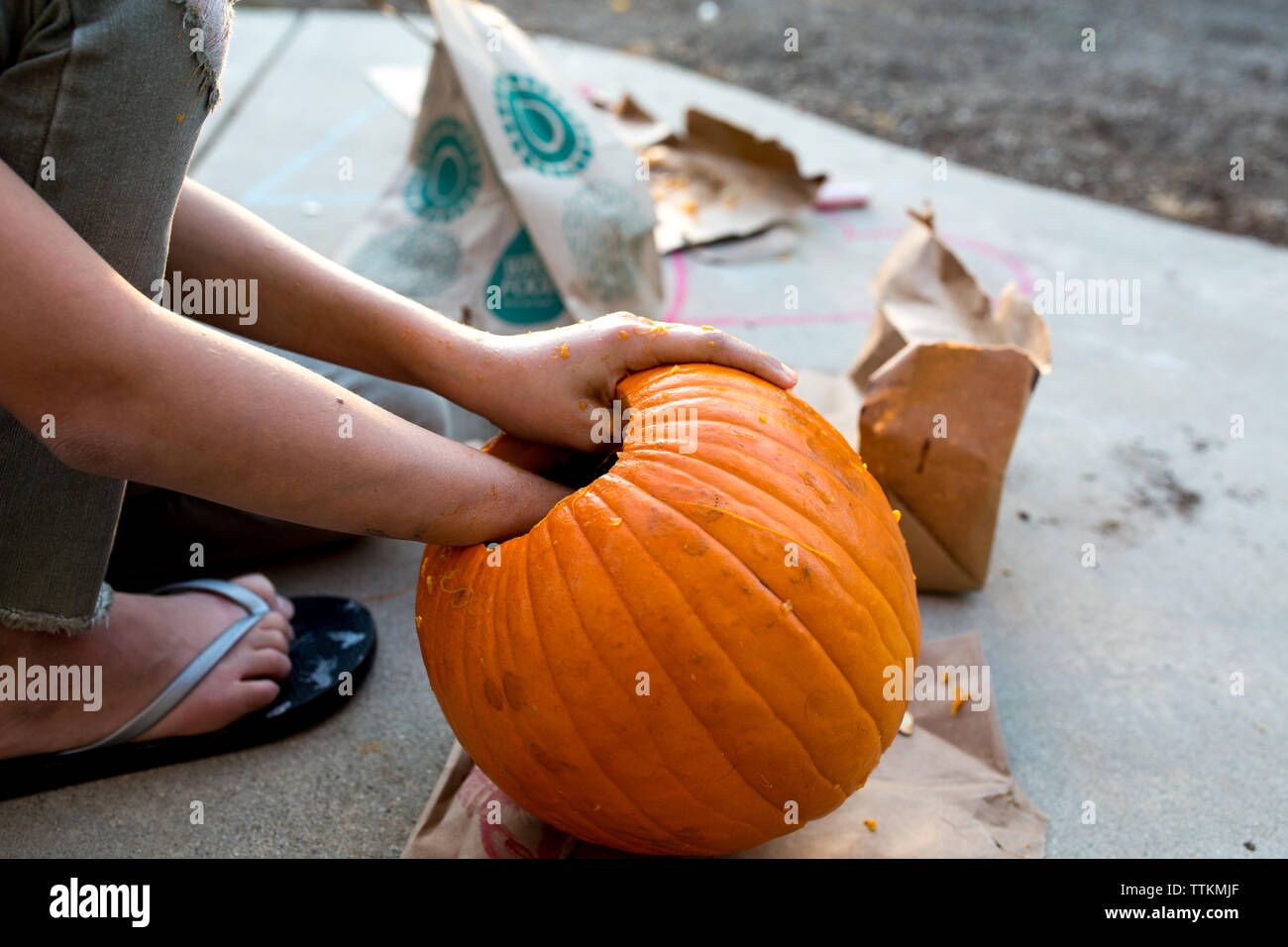 Girl reaches into pumpkin during the carving process Stock Photo
