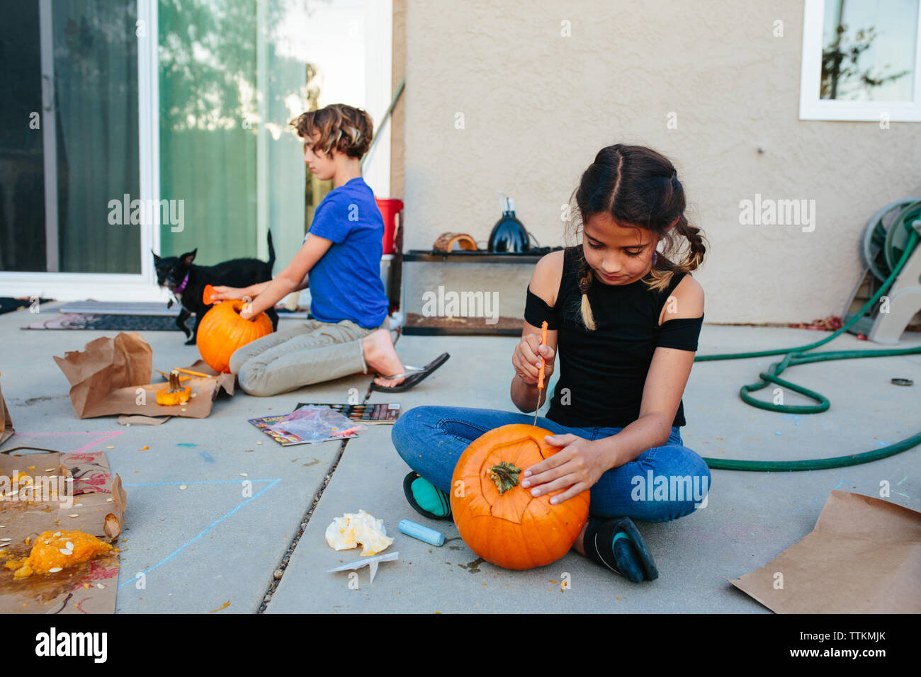 Two girls carve pumpkins outside at dusk Stock Photo - Alamy