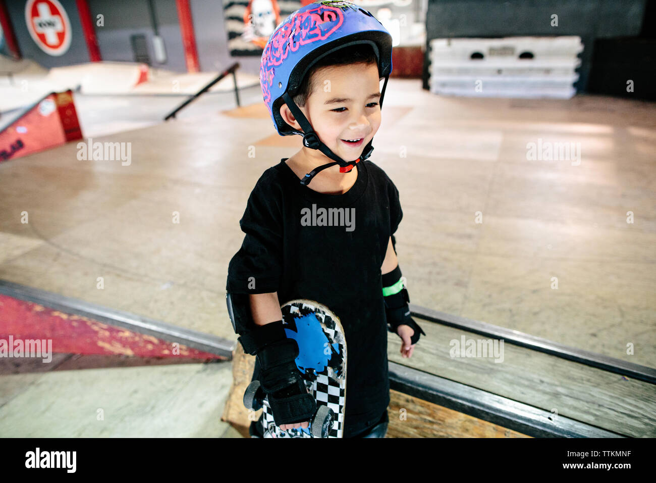 Young boy smiles as he holds his skateboard in a skatepark Stock Photo ...