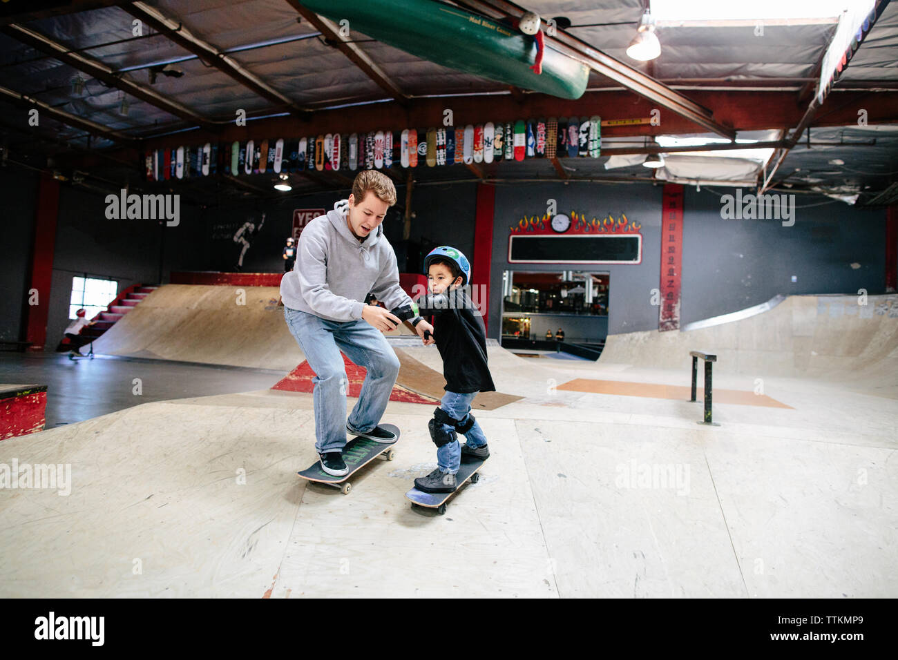 Skateboard instructor holds both hands of student going down a ramp ...