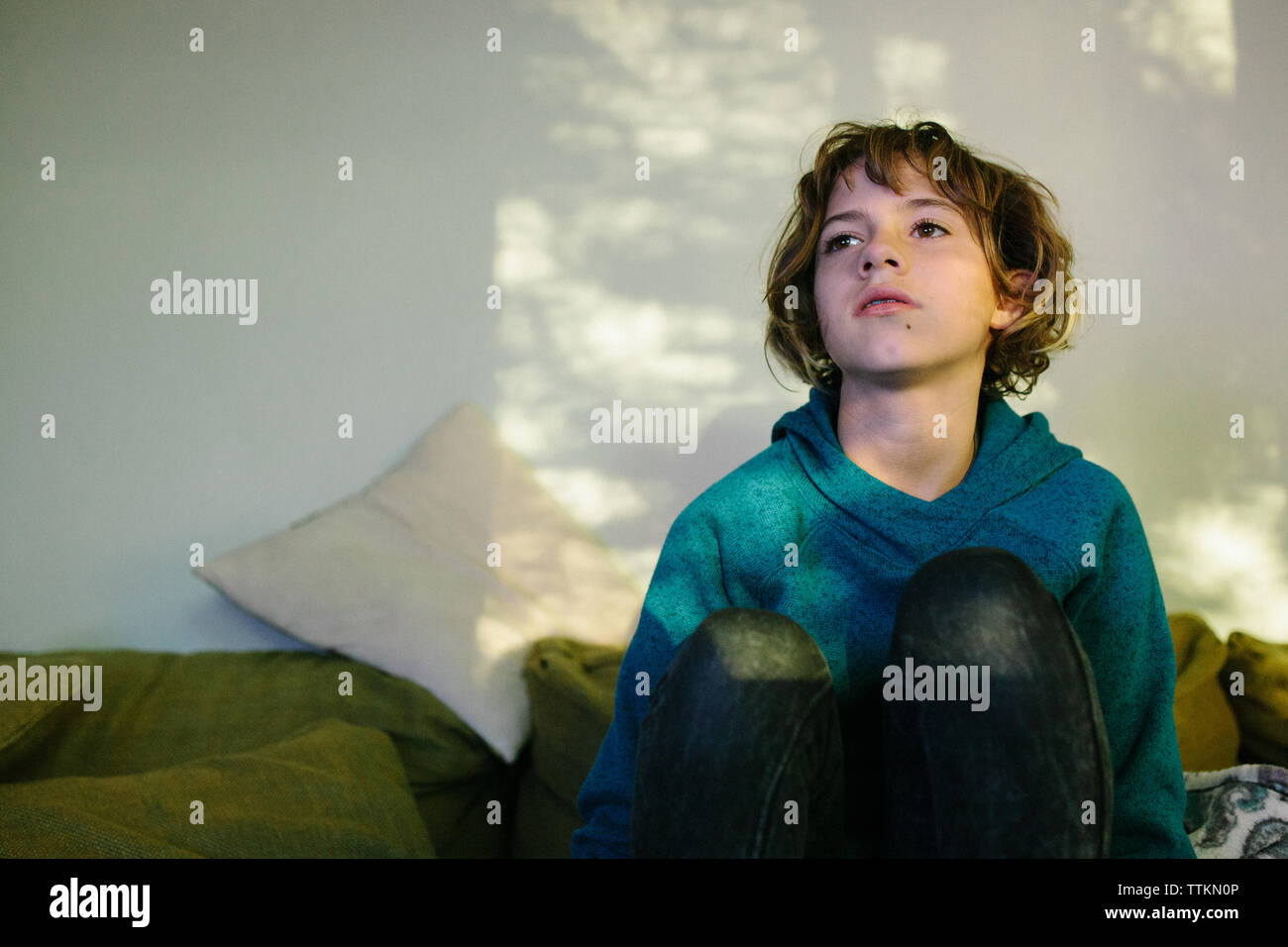 Teen Girl With Messy Short Hair Sits By Dappled Window Light Stock