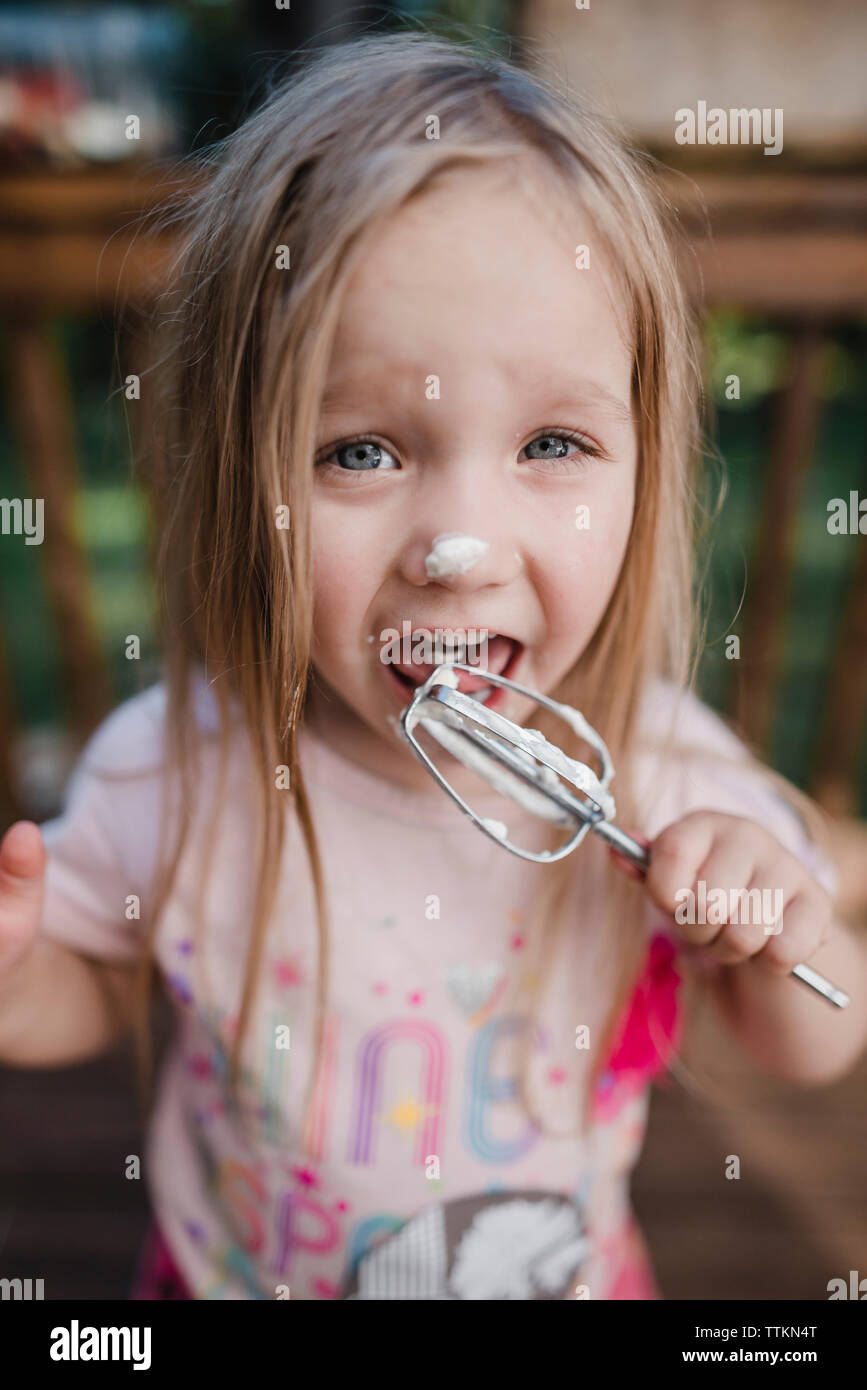 Portrait of girl licking cream from whisk Stock Photo