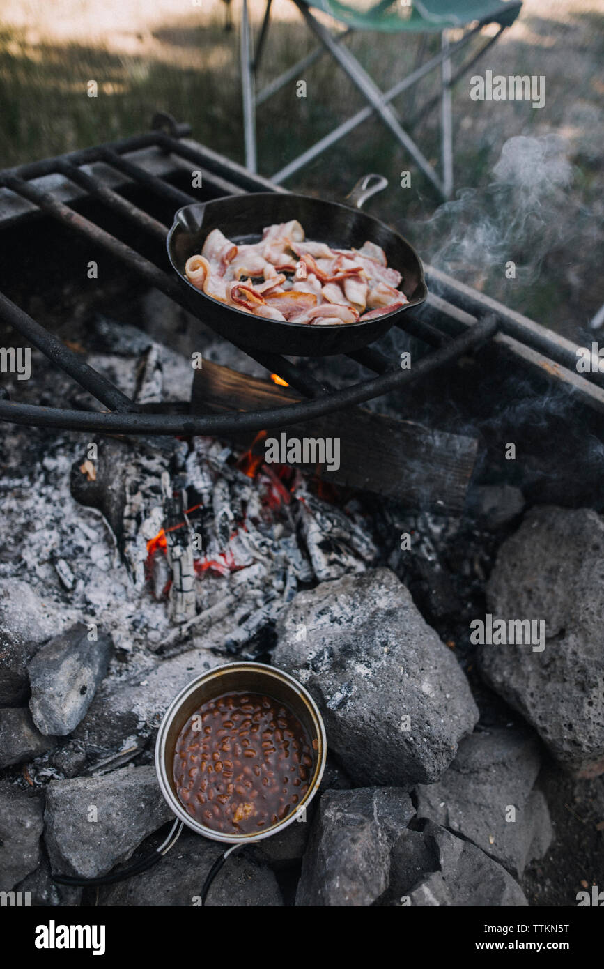 High angle view of bacon in skillet being cooked on open fire at campsite Stock Photo