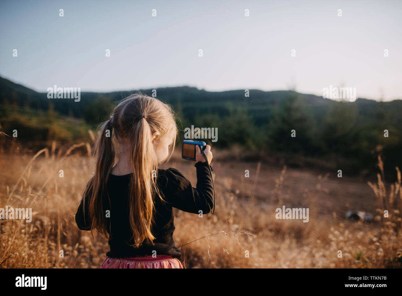 Girl with pigtails photographing while standing on field Stock Photo
