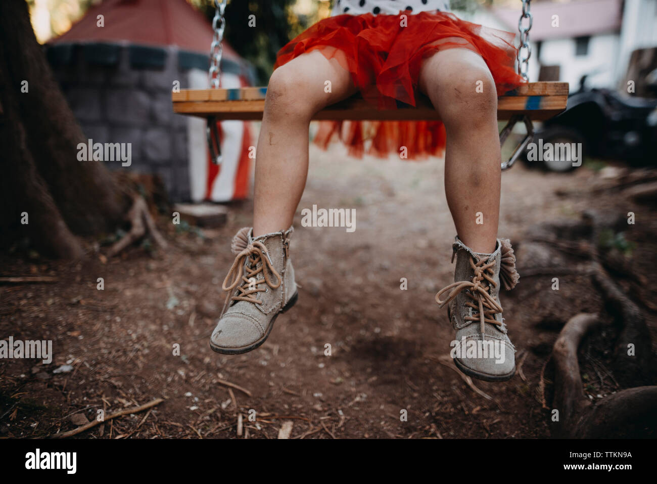 Low section of girl sitting on swing at backyard Stock Photo - Alamy