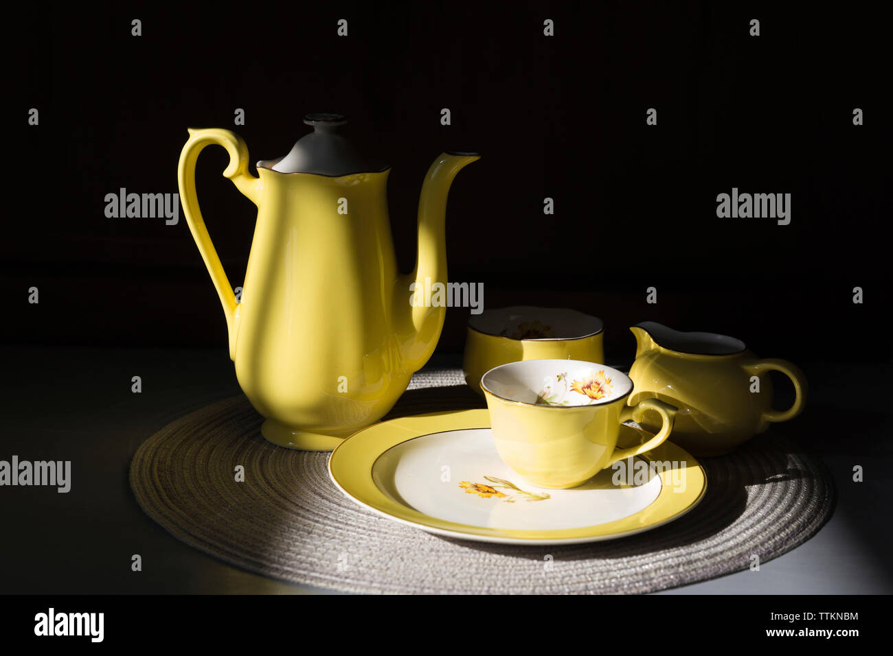 Close-up of crockery on place mat in darkroom Stock Photo