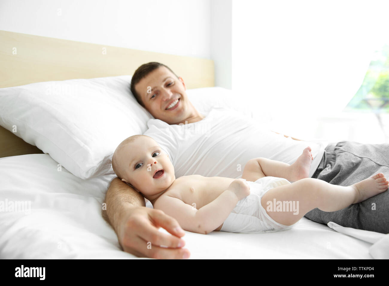 Father with son lying on bed Stock Photo - Alamy