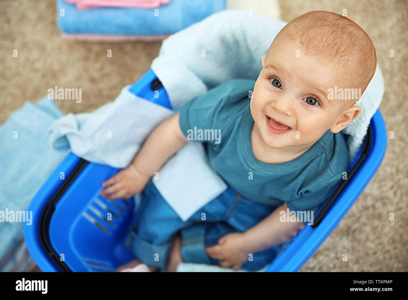 Smiling adorable baby with clothes in plastic basket Stock Photo - Alamy