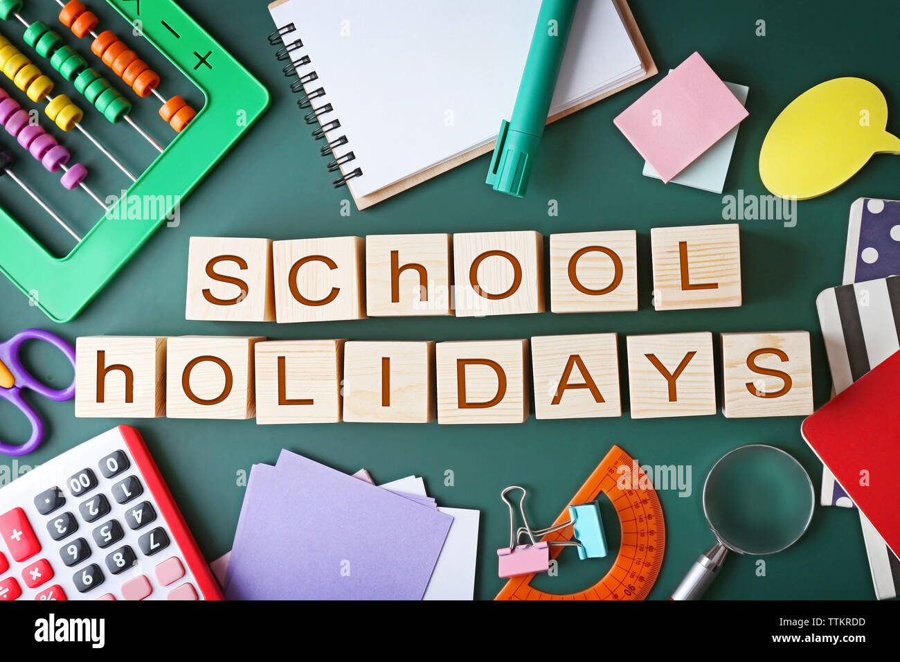 Colourful stationery and words SCHOOL HOLIDAYS on chalkboard Stock Photo